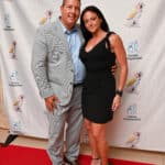 A couple posing on a red carpet in front of a Canine Companions backdrop