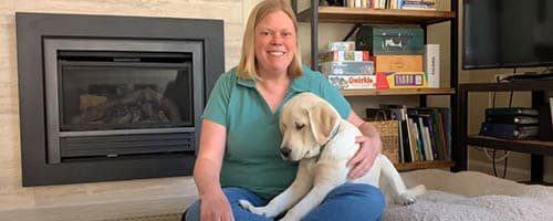 Smiling woman sits with a puppy in her lap